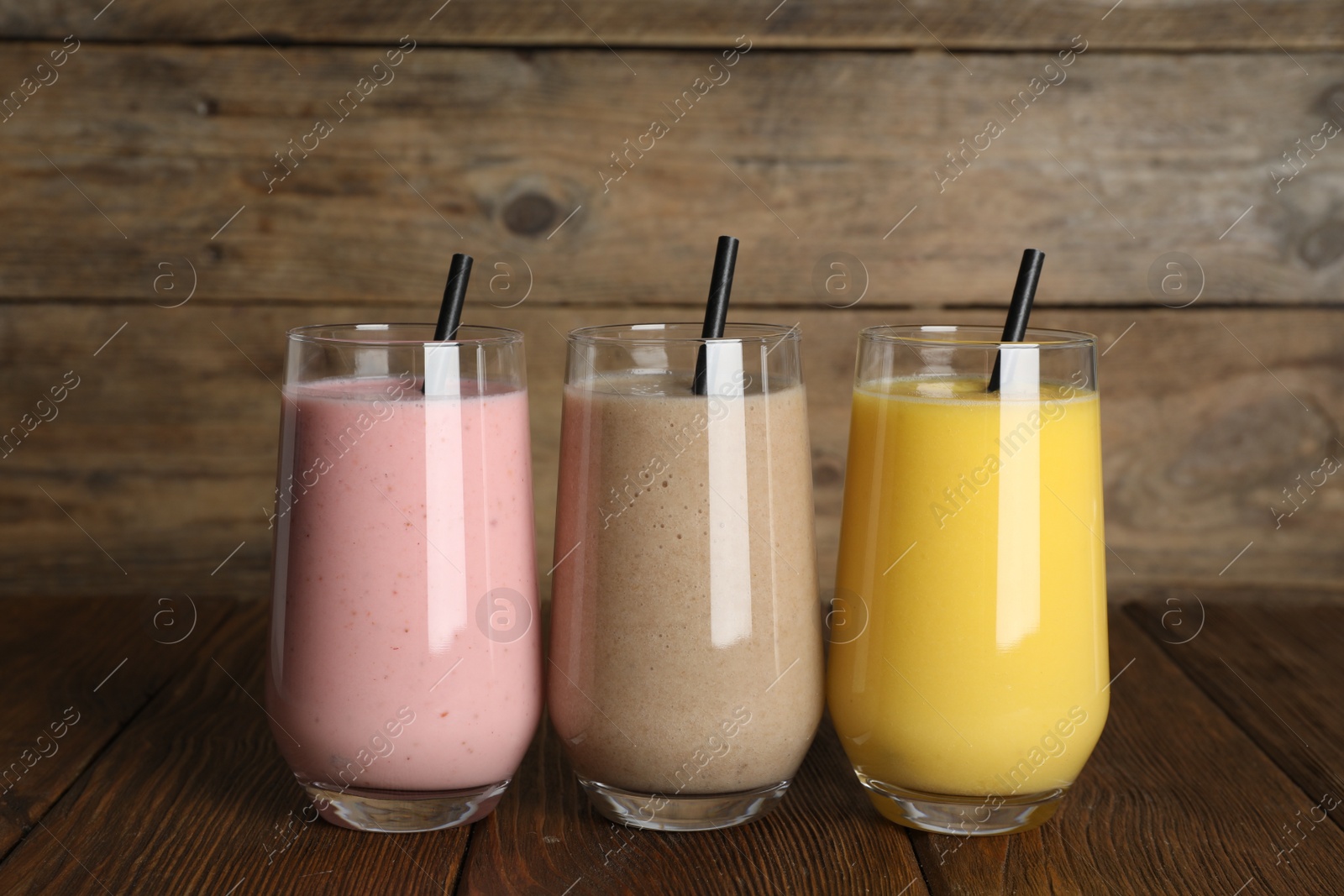 Photo of Glasses with different smoothies on wooden table