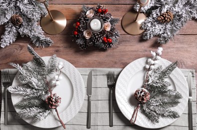 Photo of Plates with cutlery and festive decor on wooden table, flat lay