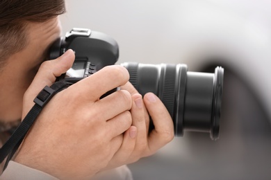 Male photographer with professional camera on blurred background, closeup