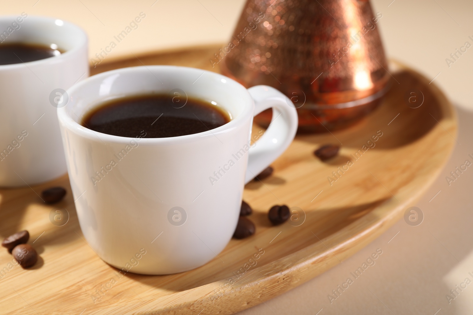 Photo of Delicious coffee in cups and beans on wooden board, closeup