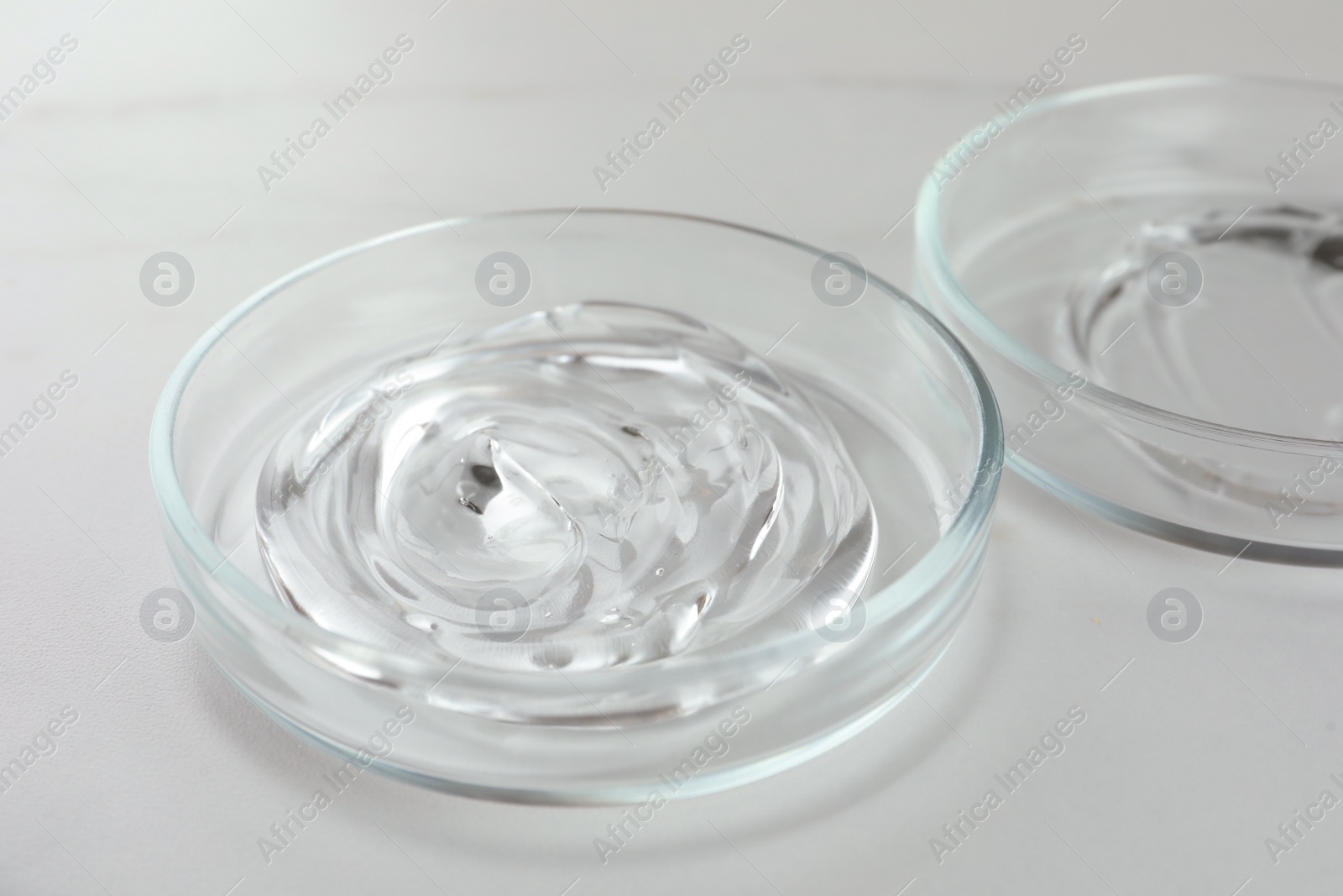 Photo of Petri dishes with liquids on white marble table, closeup