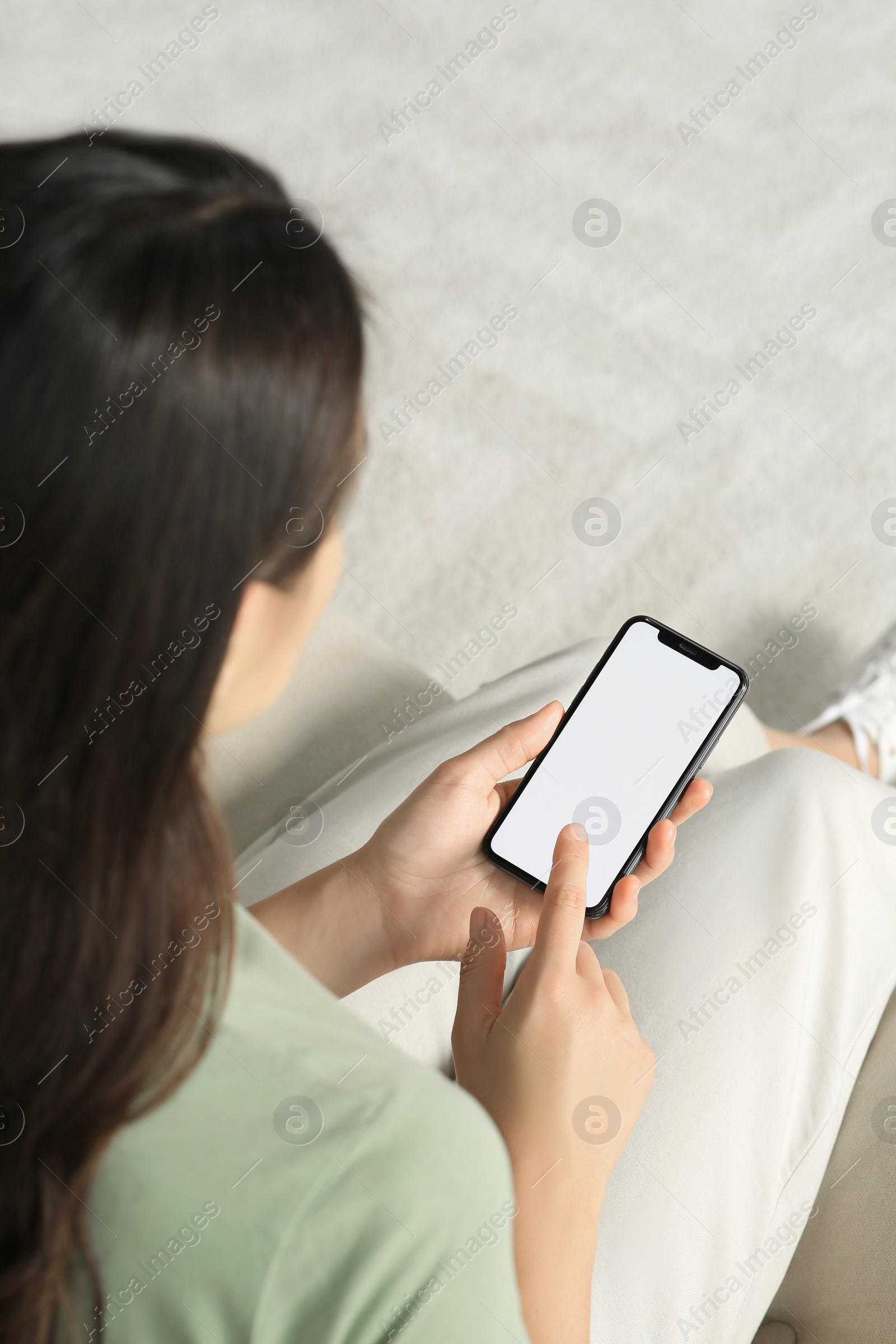 Photo of Young woman with smartphone on sofa indoors, closeup