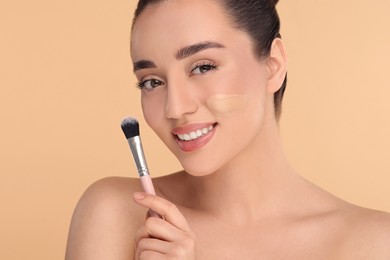 Woman with swatch of foundation holding makeup brush on beige background