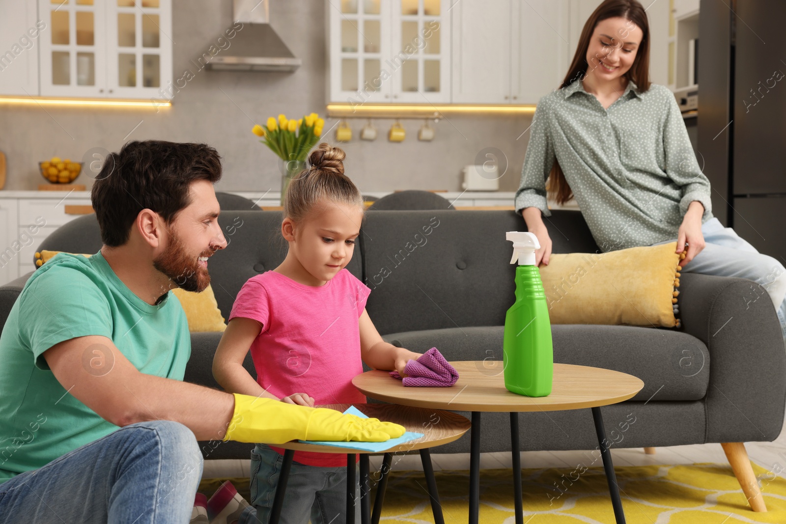 Photo of Spring cleaning. Parents with their daughter tidying up living room together