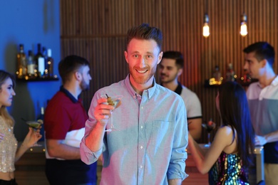 Young man with glass of martini cocktail at party