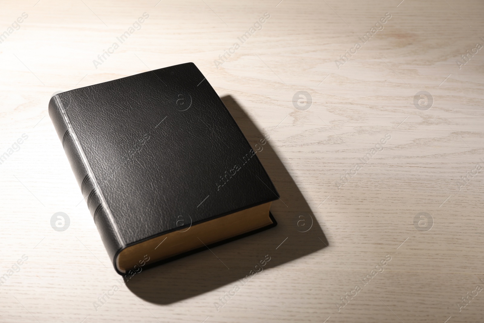 Photo of Bible on white wooden table, space for text. Christian religious book