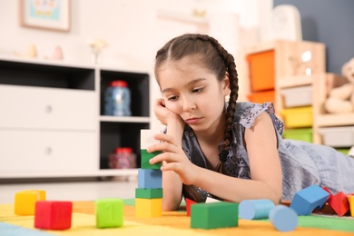 Little autistic girl playing with cubes at home