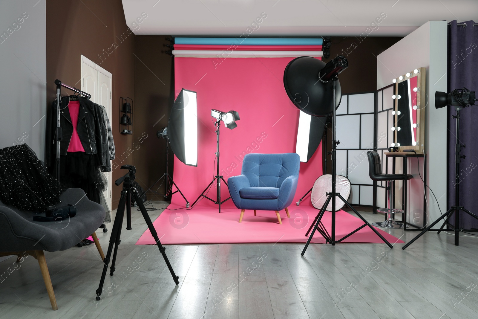 Photo of Stylish blue armchair in photo studio with professional equipment