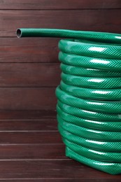 New green garden hose on wooden table