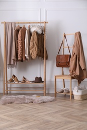 Rack with stylish warm clothes, shoes and accessories in modern dressing room