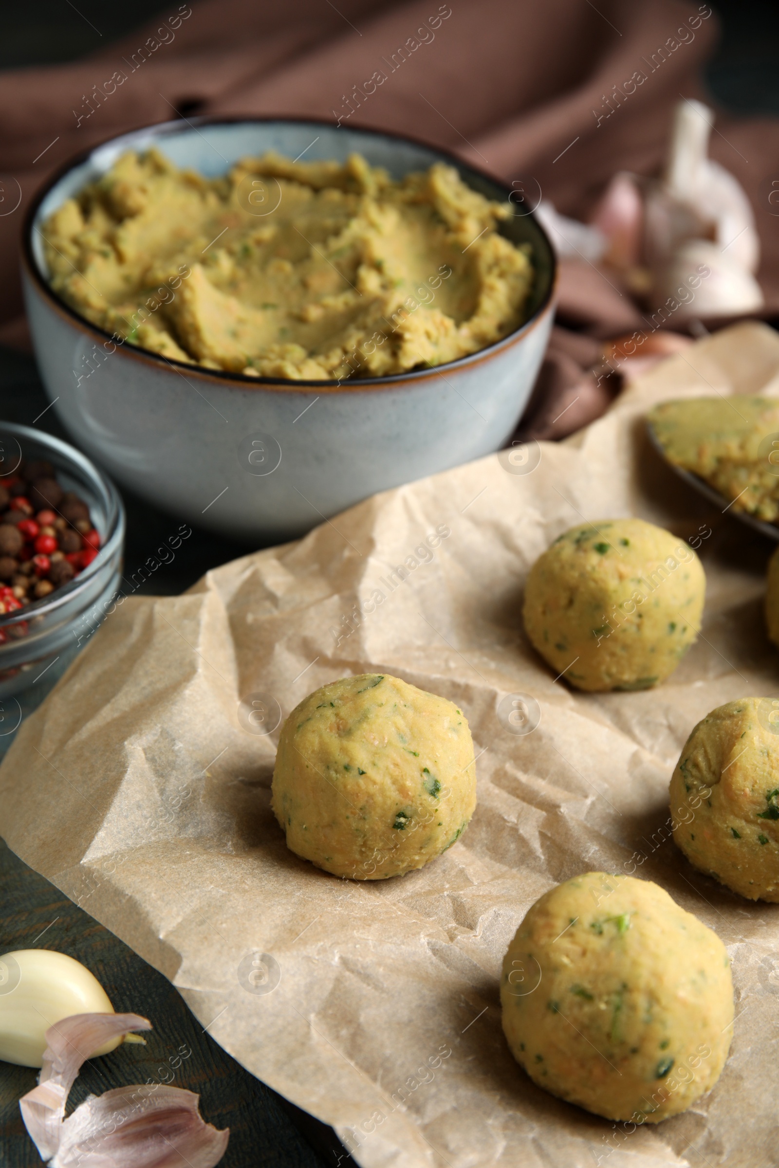 Photo of Raw falafel balls and ingredients on wooden table, closeup