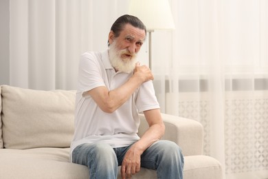 Senior man suffering from pain in shoulder at home. Rheumatism symptom