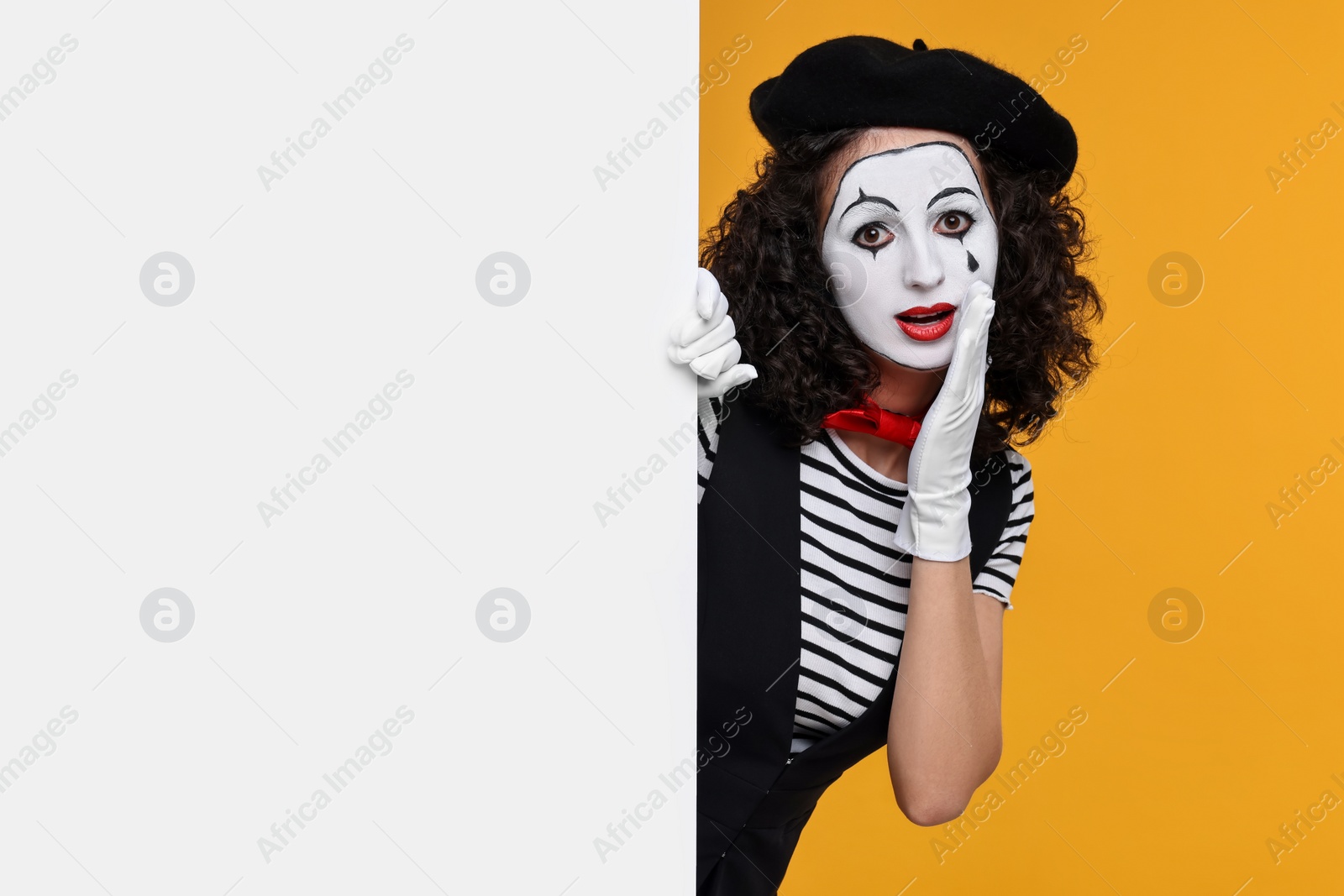 Photo of Funny mine with blank poster posing on orange background, space for text