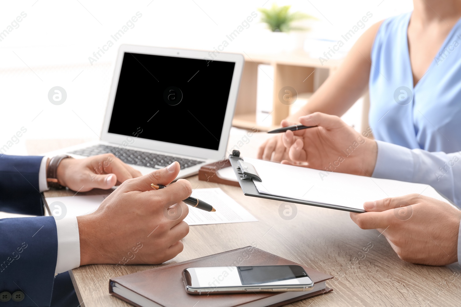 Photo of Lawyer working with clients at table in office, focus on hands