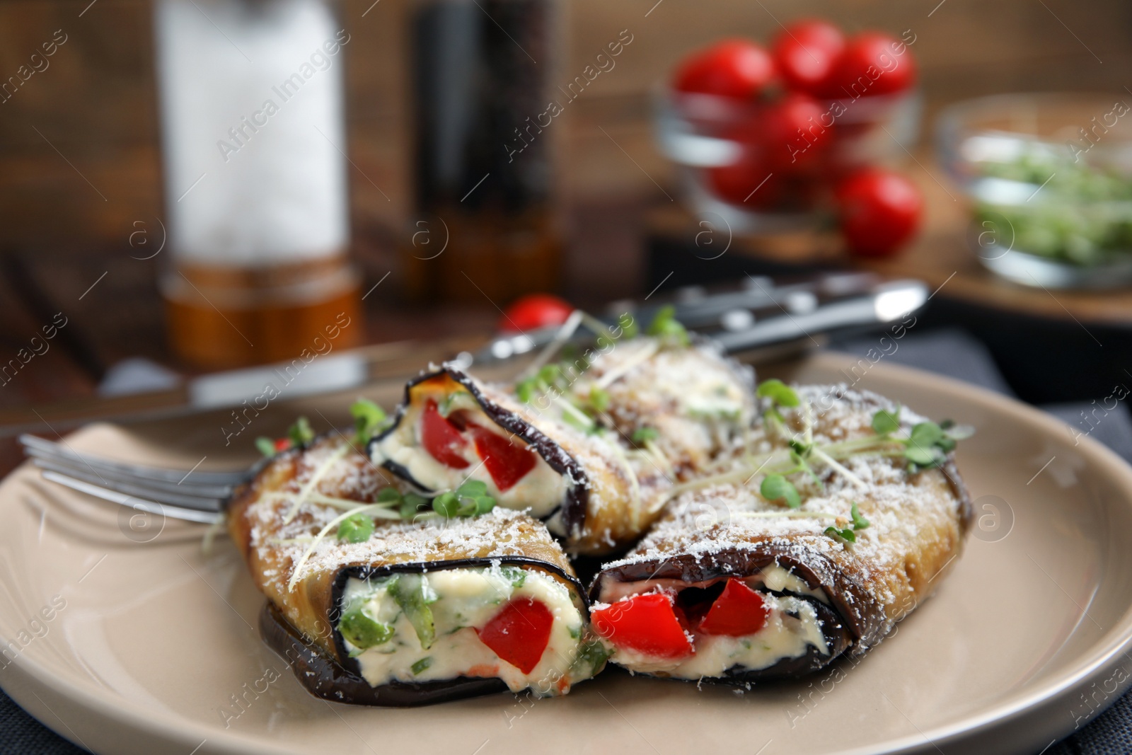 Photo of Delicious baked eggplant rolls with cheese, tomato and microgreens on plate, closeup