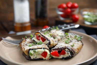 Delicious baked eggplant rolls with cheese, tomato and microgreens on plate, closeup