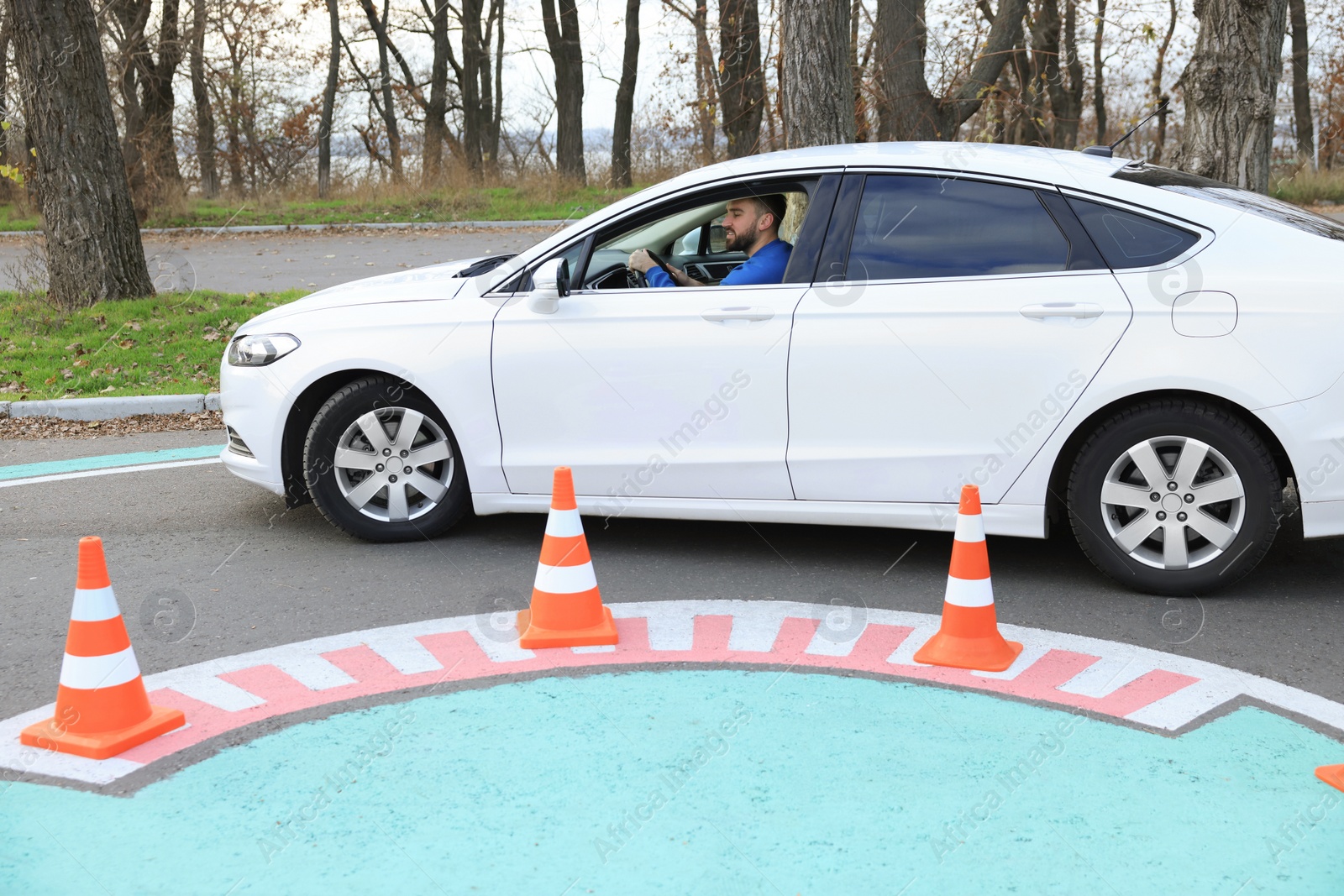 Photo of Young man in car on test track with traffic cones. Driving school