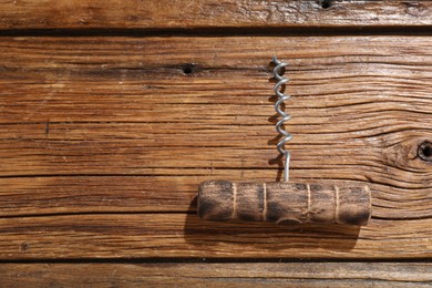 Photo of One corkscrew on wooden table, top view. Space for text