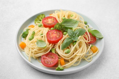 Plate of delicious pasta primavera on light gray table, closeup