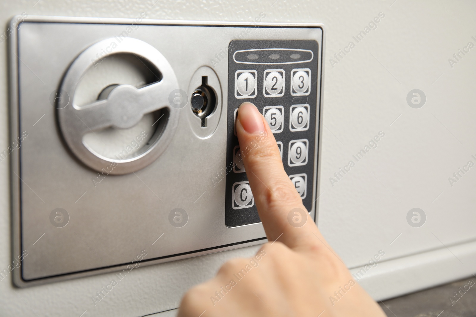 Photo of Woman opening steel safe with electronic lock, closeup