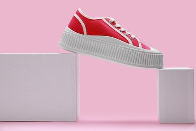 Photo of Stylish presentation of red classic old school sneaker on pink background