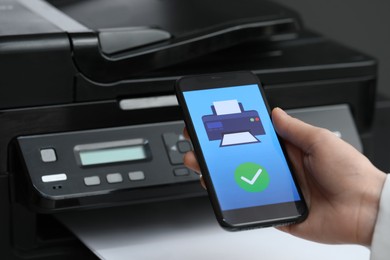 Photo of Man using printer management application on mobile phone indoors, closeup