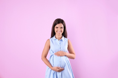 Photo of Happy pregnant woman posing on color background