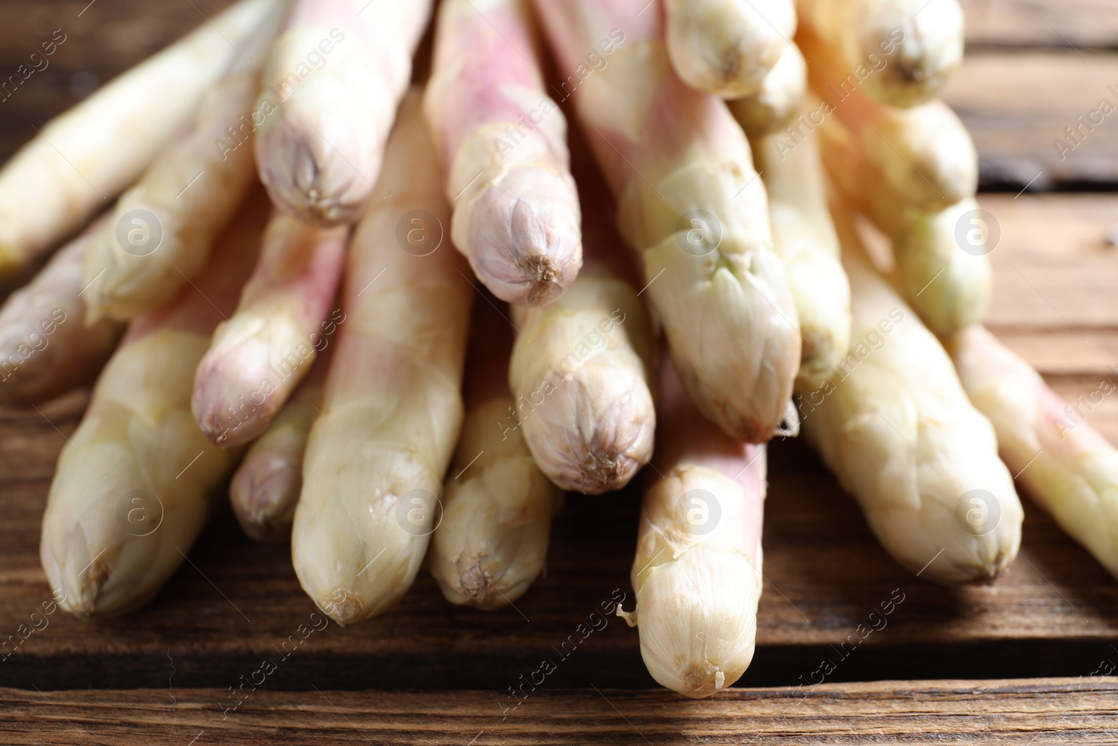 Photo of Pile of fresh white asparagus on wooden table, closeup