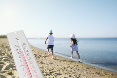 Image of Weather thermometer and little children running on sandy beach. Heat stroke warning