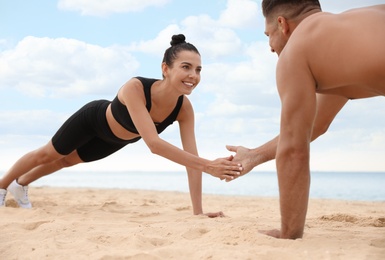 Photo of Couple doing exercise together on beach. Body training