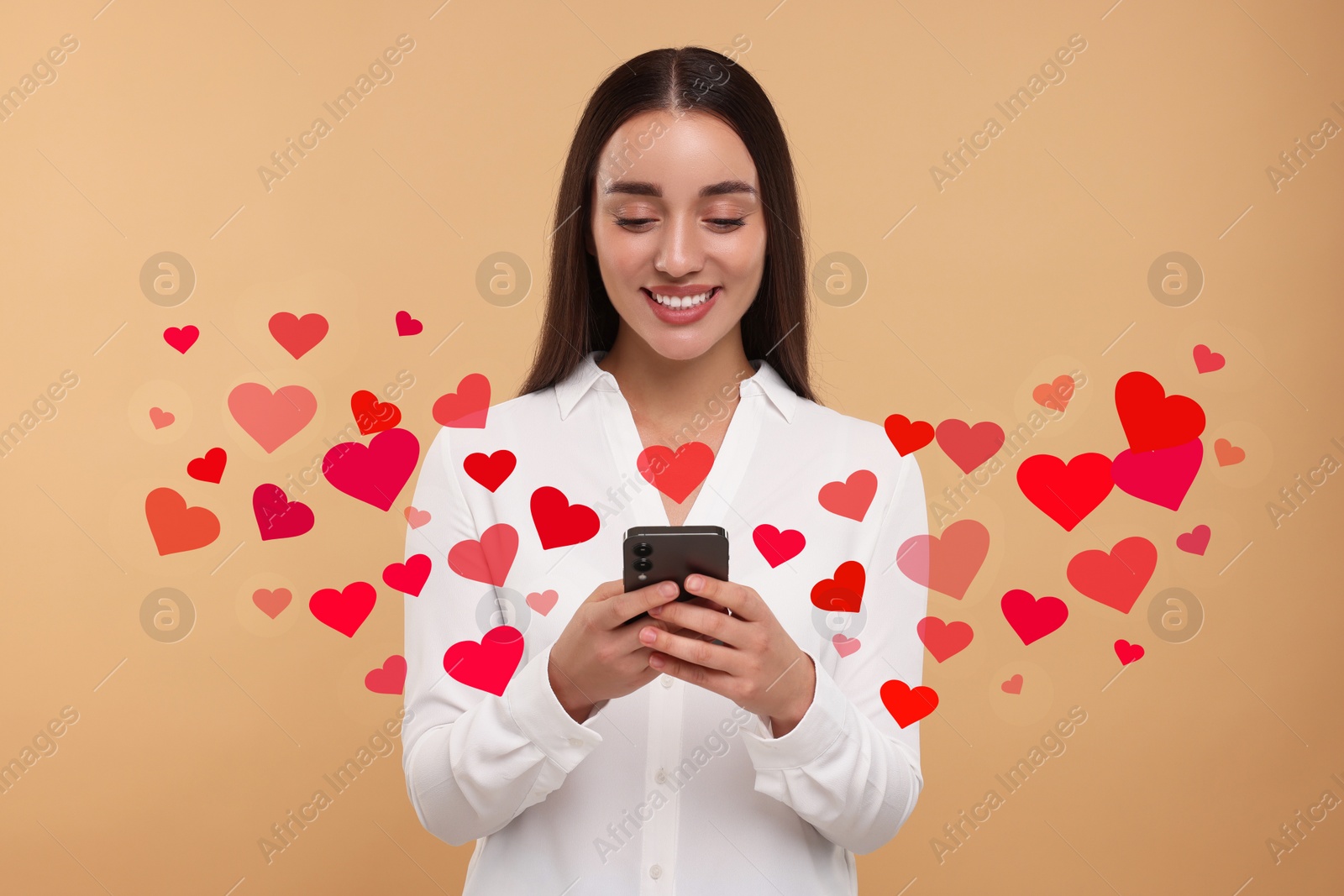 Image of Long distance love. Woman chatting with sweetheart via smartphone on dark beige background. Hearts flying out of device and swirling around her