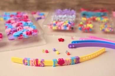 Photo of Handmade jewelry kit for kids. Colorful beads, and wristbands on beige background, closeup
