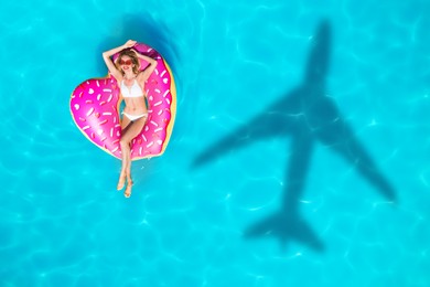 Image of Shadow of airplane and happy woman on inflatable ring in swimming pool, top view. Summer vacation