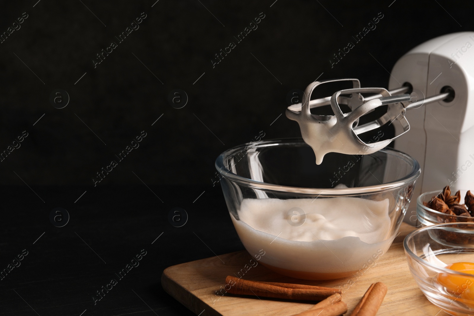 Photo of Different ingredients and mixer on black table, space for text. Cooking delicious eggnog
