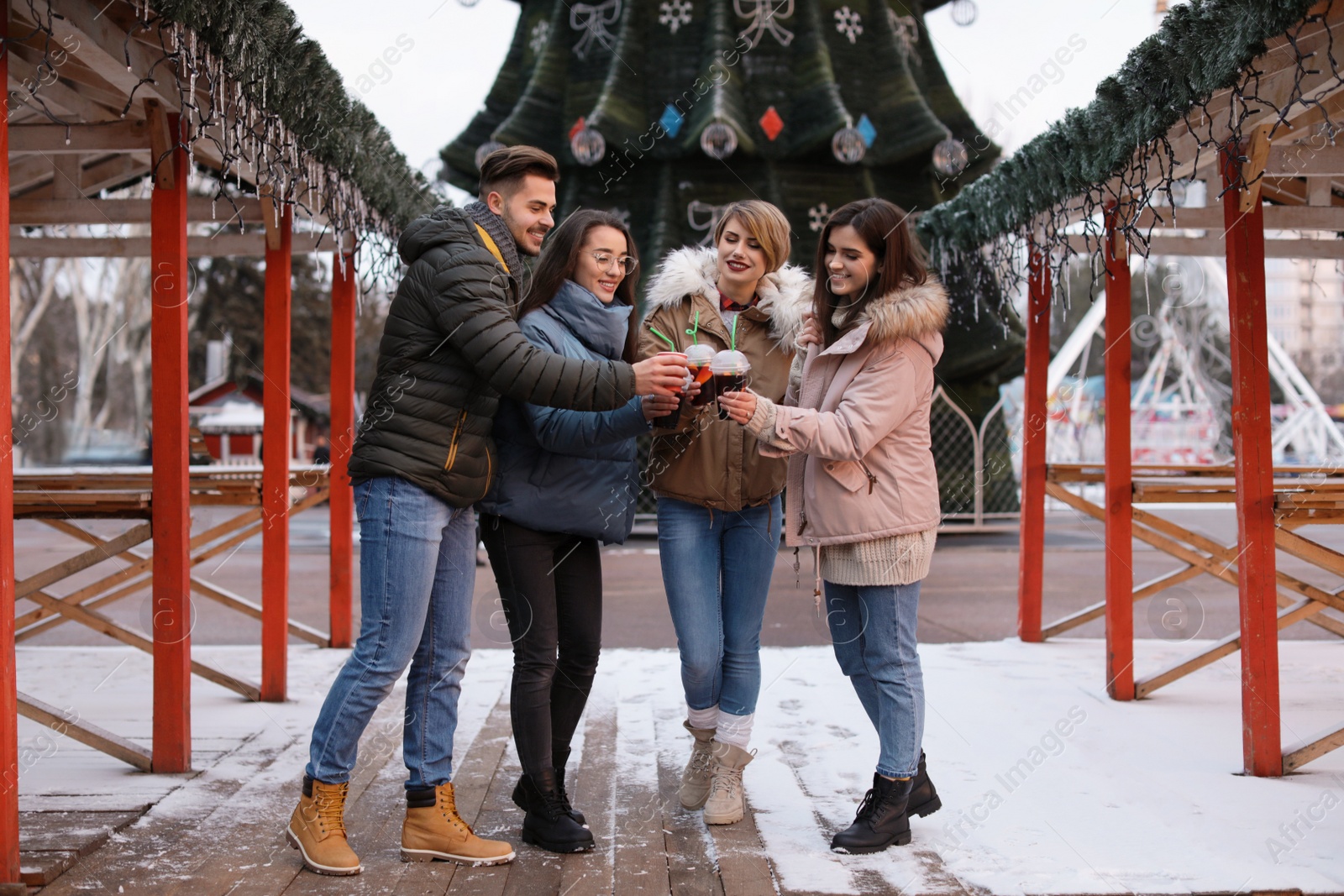 Photo of Friends with cups of mulled wine at winter fair