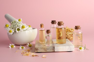 Photo of Aromatherapy. Different essential oils and flowers on pink background