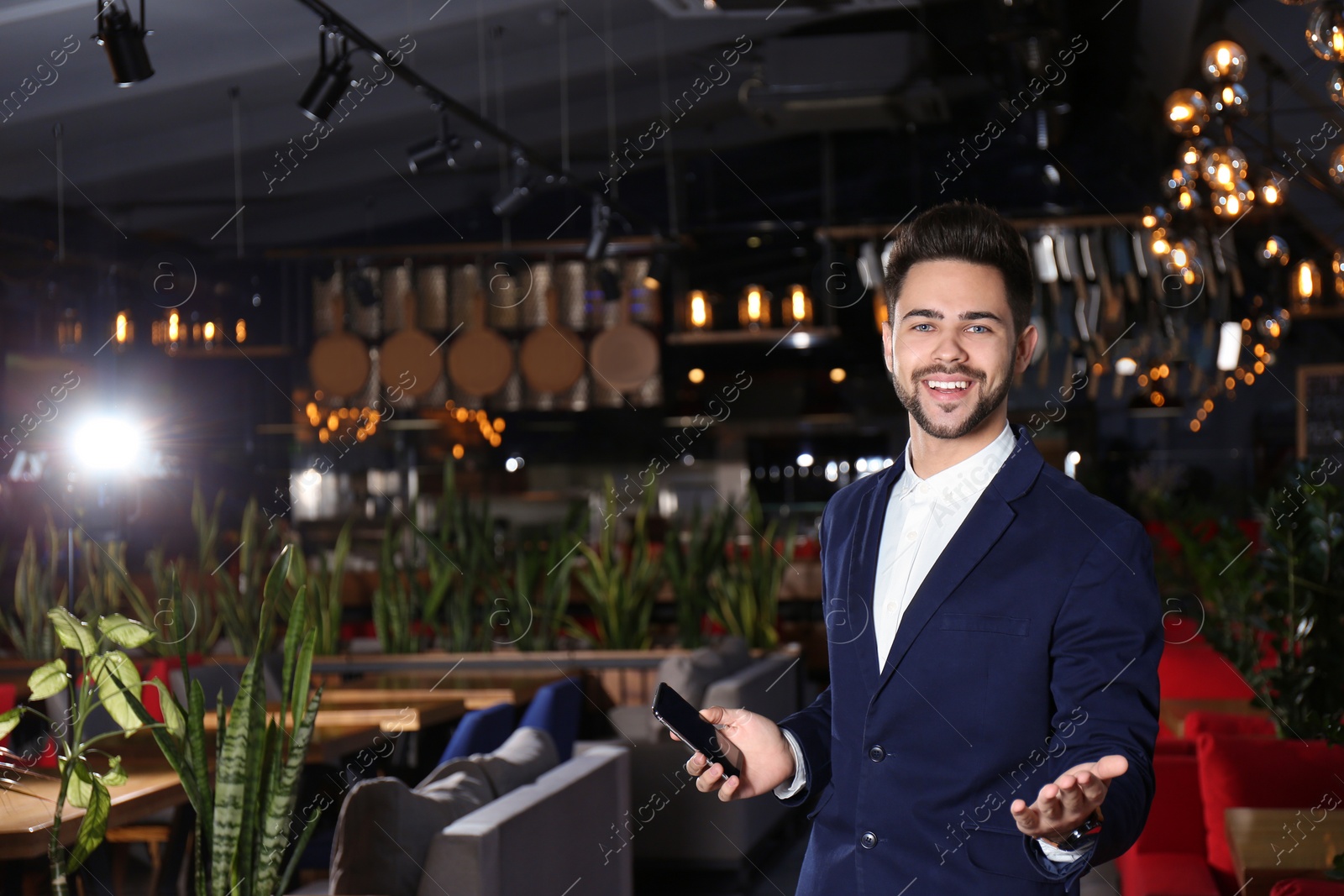 Photo of Young business owner with phone in his cafe. Space for text