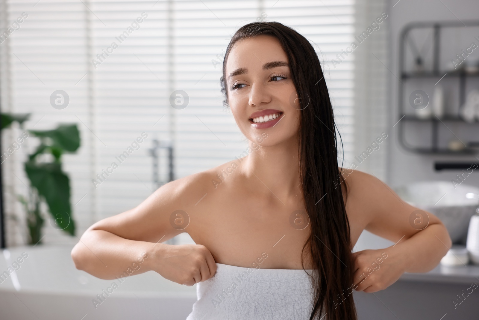 Photo of Smiling young woman after shower in bathroom