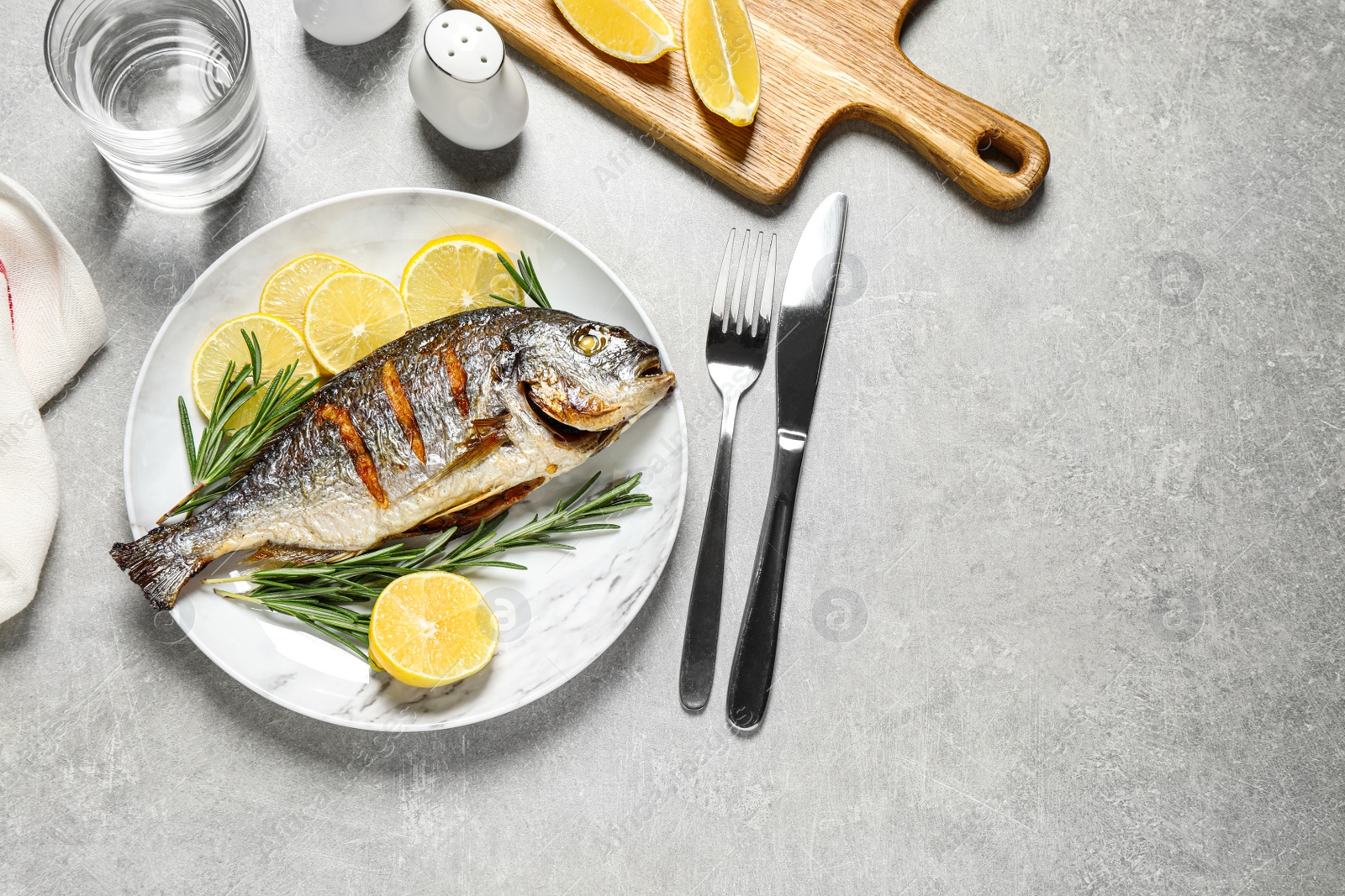 Photo of Delicious roasted fish with lemon on grey table, flat lay. Space for text