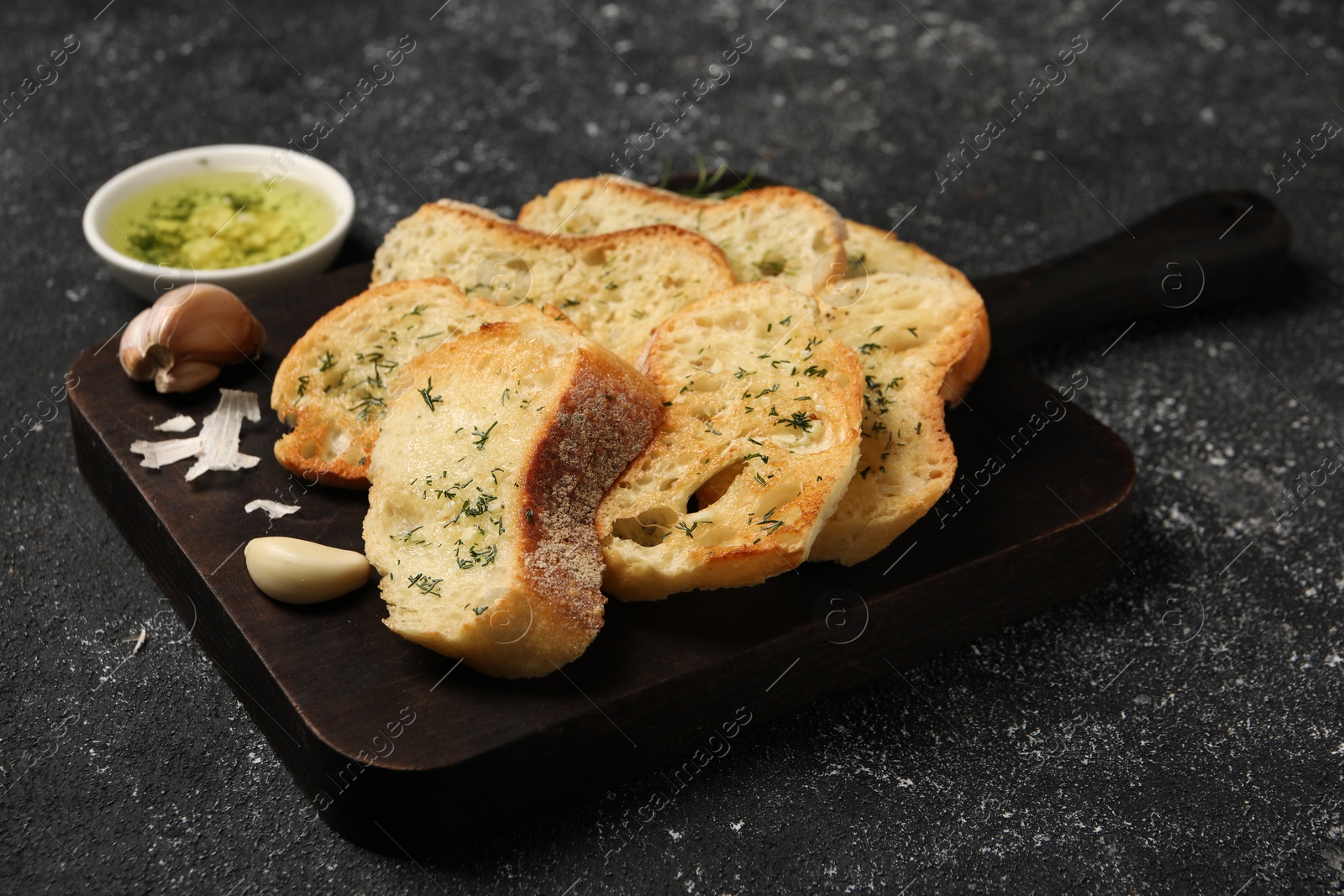 Photo of Tasty baguette with garlic and dill served on grey textured table