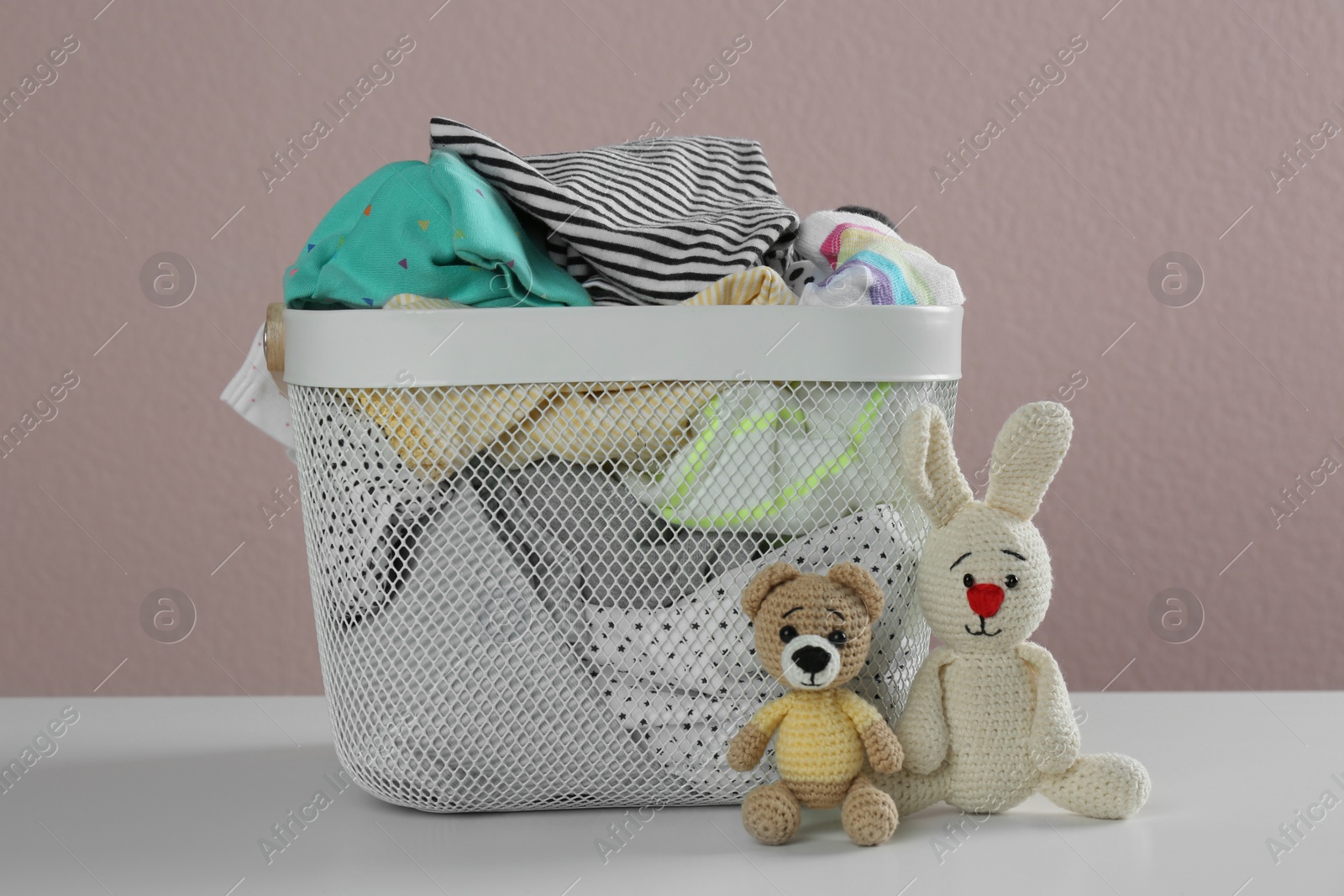 Photo of Laundry basket with different children's clothes and toys on white table