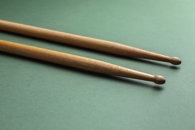 Photo of Two wooden drum sticks on olive background, closeup