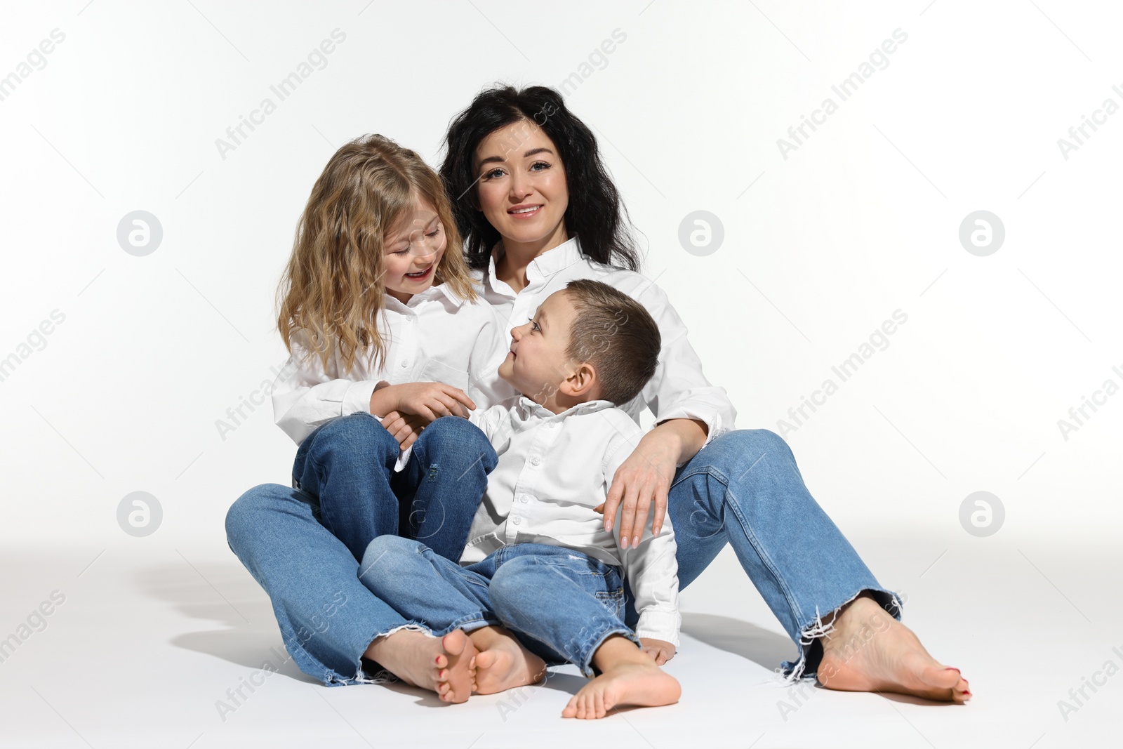 Photo of Little children with their mother sitting together on white background