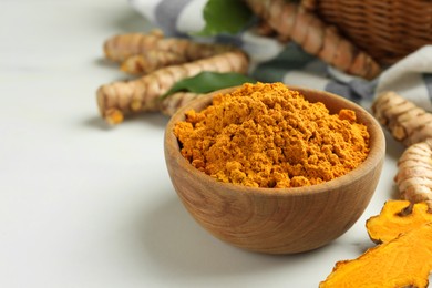 Photo of Aromatic turmeric powder and raw roots on white table, closeup. Space for text