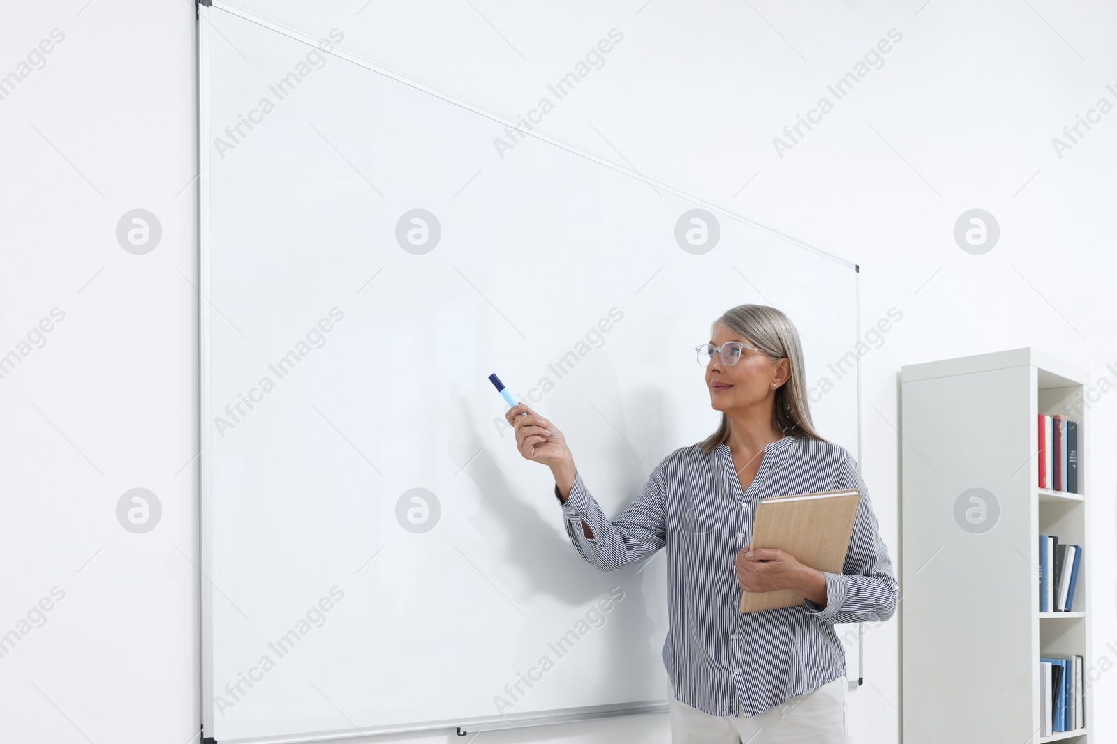 Photo of Professor giving lecture near whiteboard in classroom, space for text