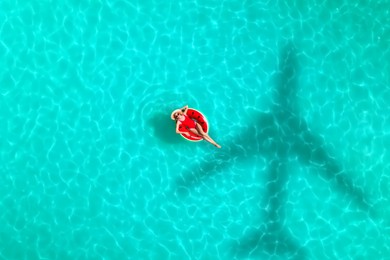 Image of Shadow of airplane and happy woman on inflatable ring in swimming pool, aerial view. Summer vacation