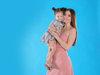 Young mother and little daughter on blue background