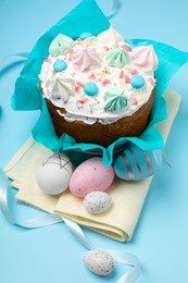 Photo of Traditional Easter cake with meringues and painted eggs on light blue background