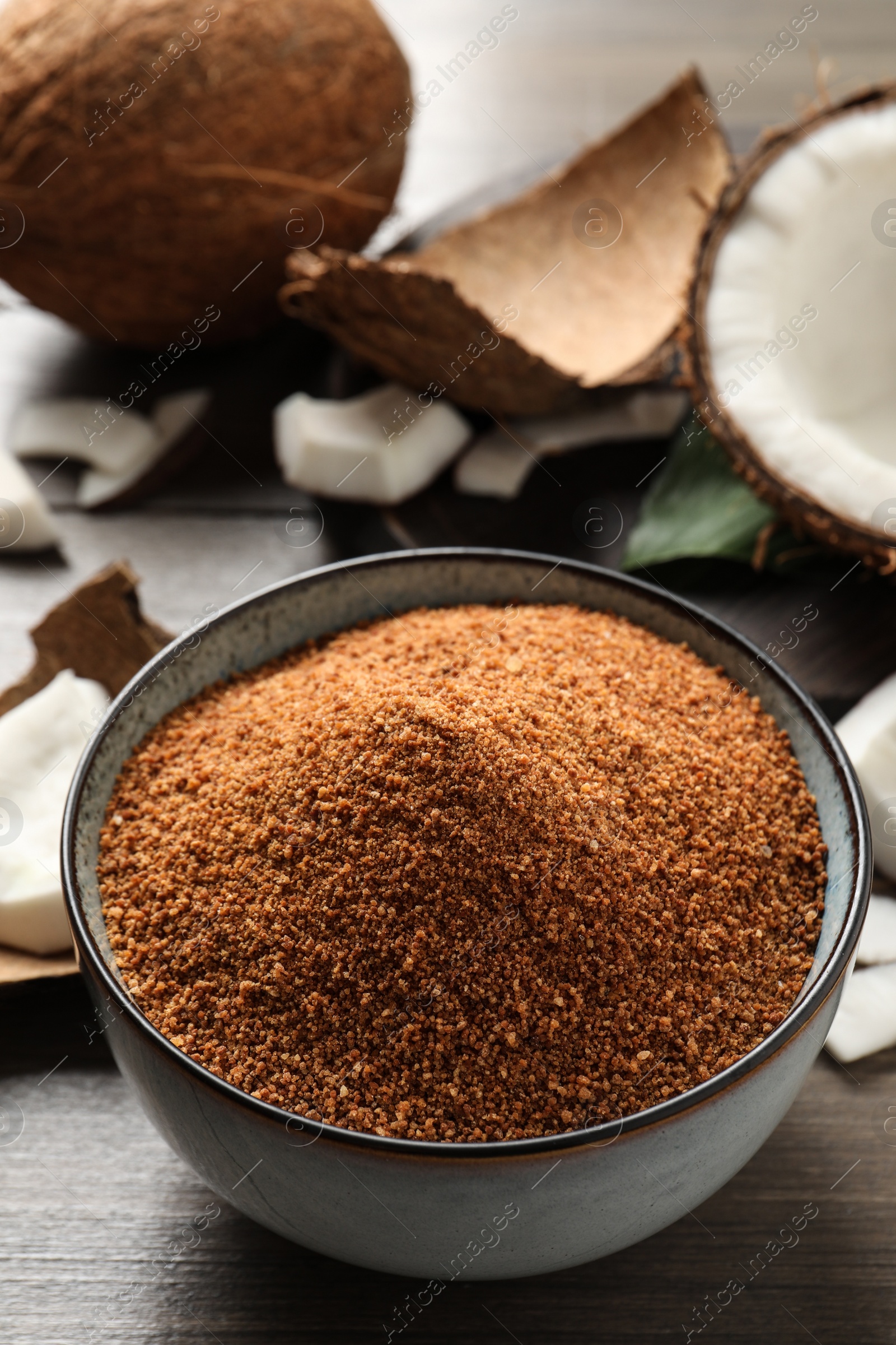 Photo of Natural coconut sugar in ceramic bowl on wooden table