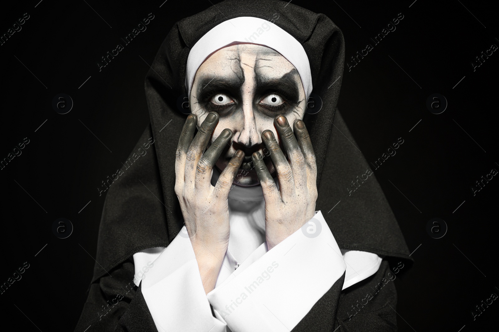 Photo of Portrait of scary devilish nun on black background. Halloween party look